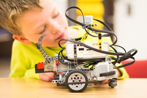 Image shows a child working on a LEGO mindstorms robot.