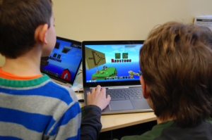 Image of student and teacher playing Minecraft on a laptop.